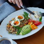 A delicious and healthy breakfast featuring avocado, eggs, and coffee served on a wooden table.