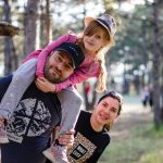 A joyful family enjoying a playful day in a sunlit forest park, capturing the essence of togetherness.